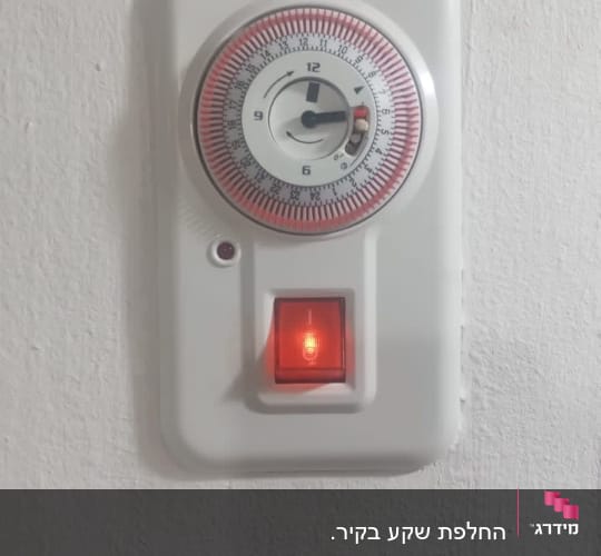 שעון טיימר עם מתג דולק על קיר לבן